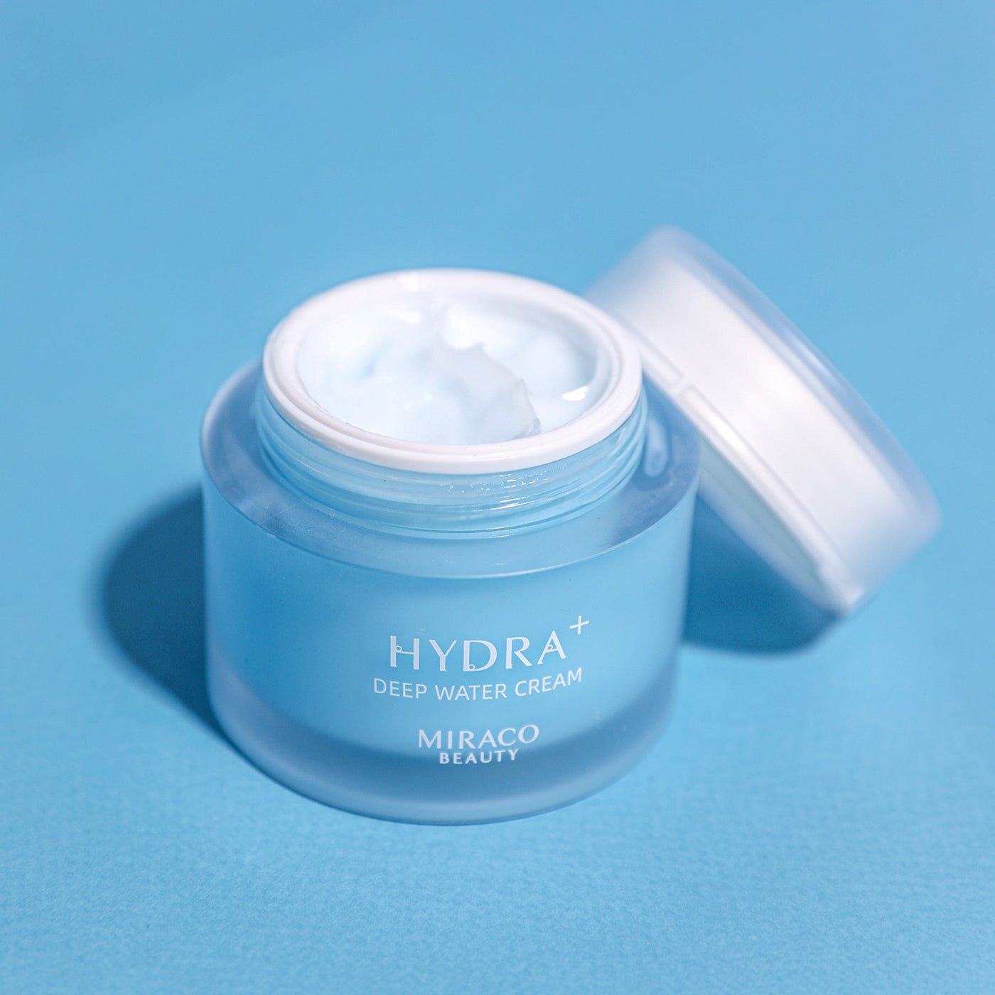 Hydra+ Deep Water Cream with texture of the cream on a light blue background
